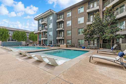 A large apartment complex with a pool and sun loungers.