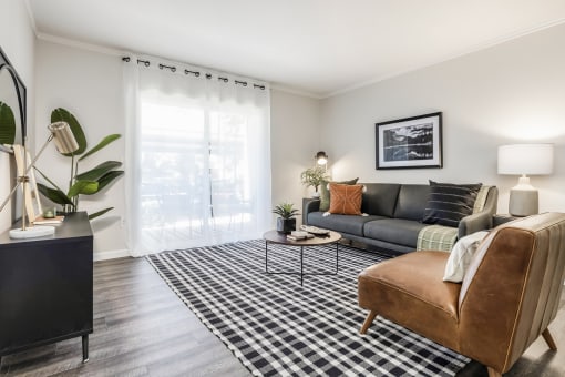 Living room with gray sofa and brown leather chair at Canyon Creek Apartments, Wilsonville