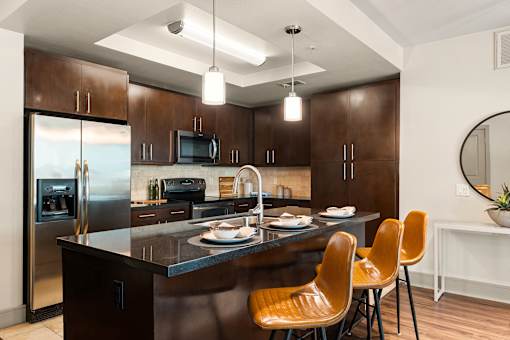 A modern kitchen with brown cabinets and a black island.
