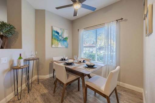 A dining room with a table set for two and a ceiling fan.