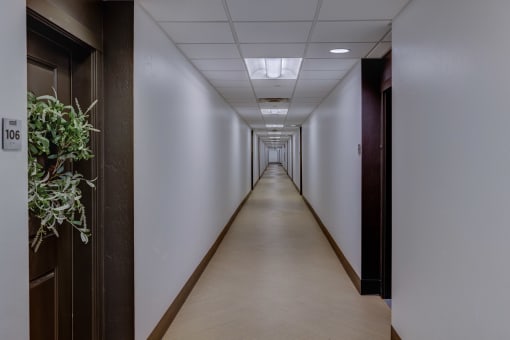 a long hallway with wood floors and white walls and wooden doors