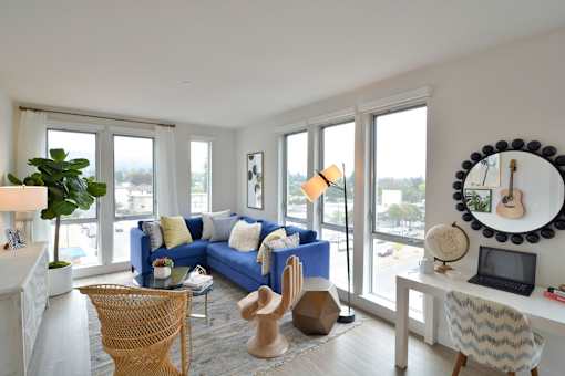 A living room with a blue couch and a guitar on the wall.