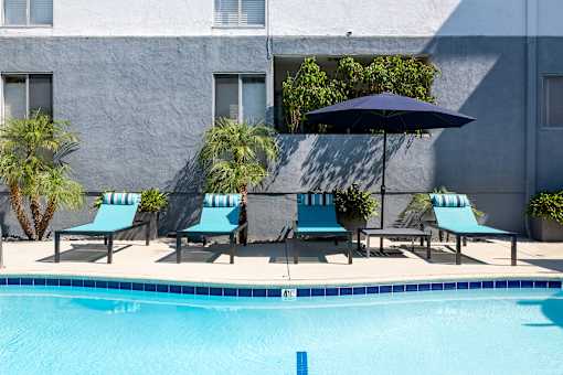 A pool with a blue umbrella and chairs at The Fulton, Los Angeles, CA, 91423