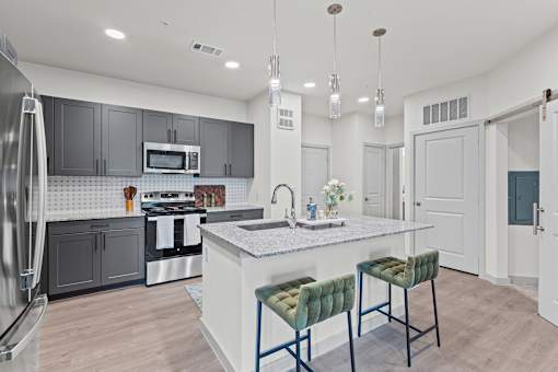 A modern kitchen with a white island and green bar stools.
