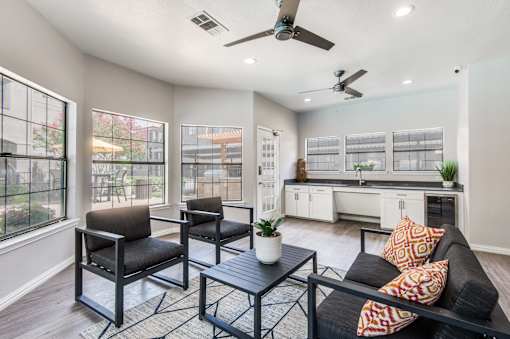 A living room with a black couch and a table with a potted plant on it.