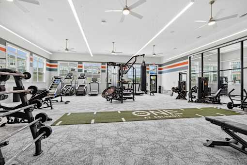 A gym with a variety of equipment including treadmills, weights, and exercise machines.