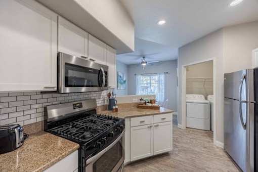 A kitchen with a black stove top oven and white cabinets.