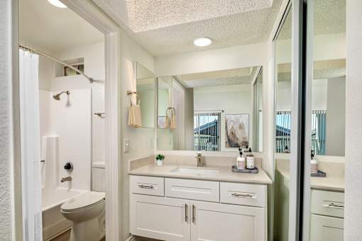A white bathroom with a toilet, sink, and mirror.
