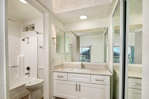 A white bathroom with a shower, sink, and mirror.