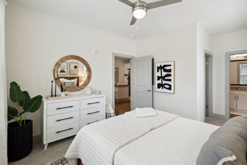 a white bedroom with a white bed and a ceiling fan