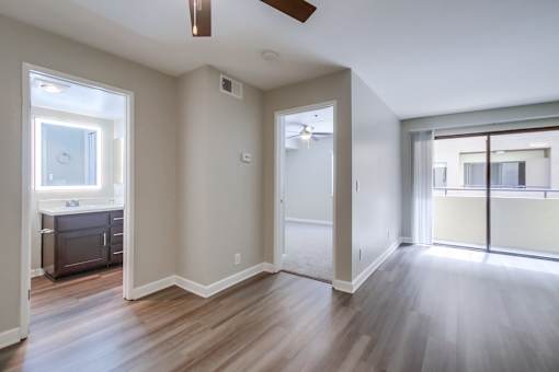 A room with a ceiling fan and sliding glass doors.