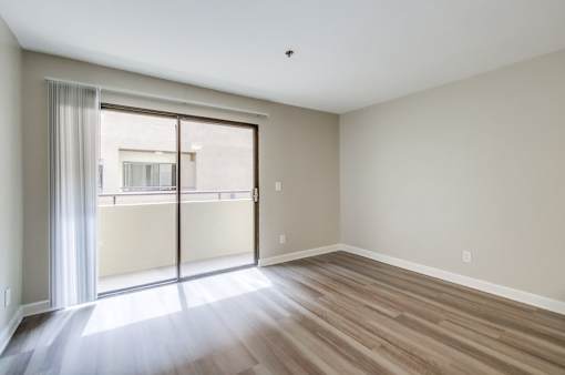 A room with a sliding glass door leading to a balcony.