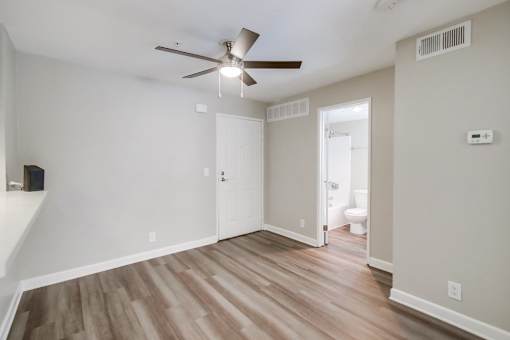 A room with a ceiling fan and wooden flooring.