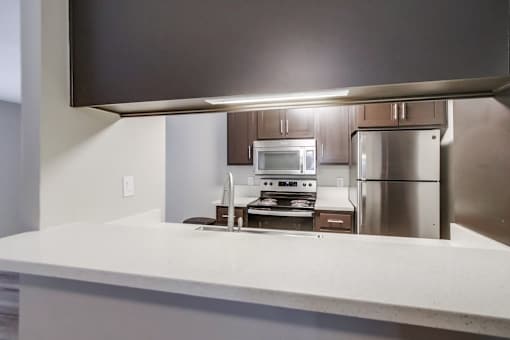 A modern kitchen with stainless steel appliances and a flat screen TV mounted above the island.