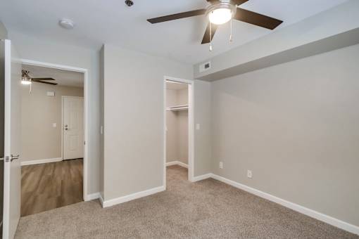 A room with a ceiling fan and carpeted floor.