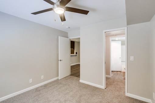 A room with a ceiling fan and two open doors.