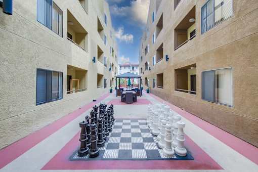 A giant chess board is set up in the courtyard of a building.