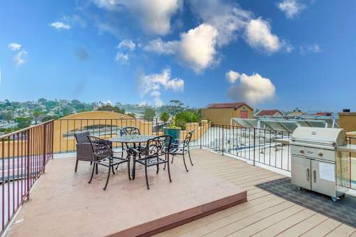 A patio with a table and chairs overlooking a cityscape.