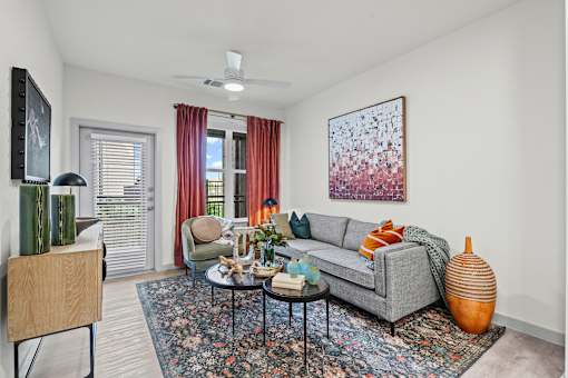 A living room with a grey couch, a coffee table, and a painting on the wall.
