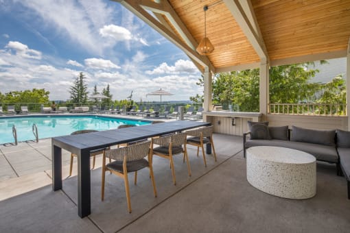 a patio with a table and chairs and a pool in the background at Arbor Heights, Tigard