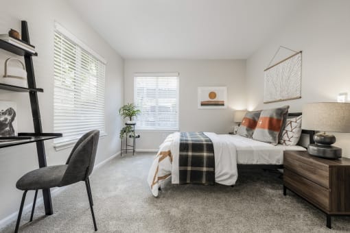 Bright bedroom with wooden nightstand and layered bedding at Canyon Creek Apartments, Wilsonville, Oregon