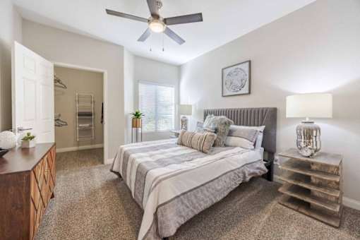 A bedroom with a bed, nightstand, and a ceiling fan.