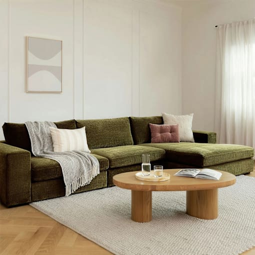 A living room with a green couch, a wooden coffee table, and a grey rug.