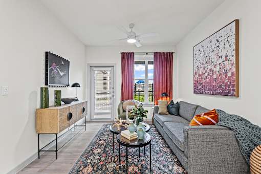 A living room with a grey couch and a large abstract painting on the wall.