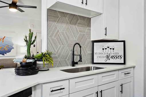 A kitchen with a white counter top and a framed sign that says