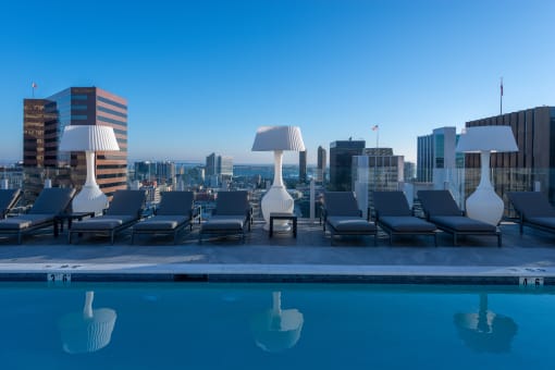 a pool with lounge chairs and lamps on top of a building at Stanza Little Italy, California, 92101