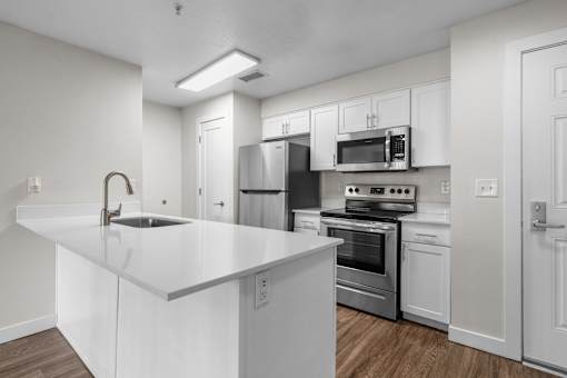 A modern kitchen with white cabinets and stainless steel appliances.