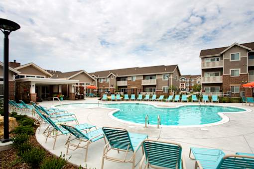 A swimming pool surrounded by chairs and buildings in the background.