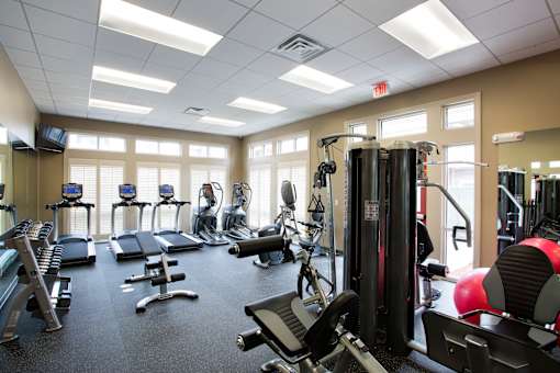 A gym with a variety of equipment including treadmills, weights, and exercise machines.