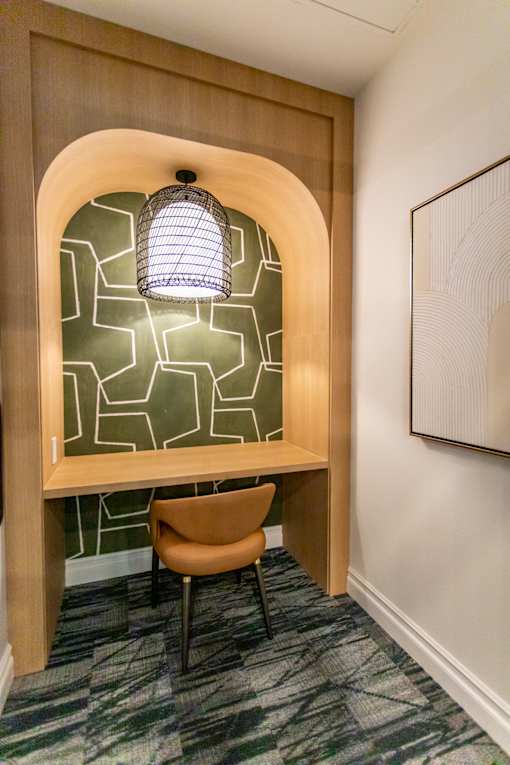 A wooden desk with a lamp and a chair in front of a geometric patterned wall.