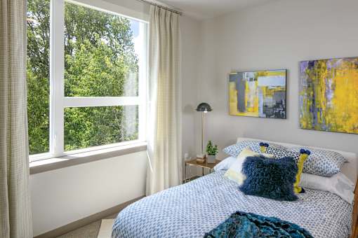 A bedroom with a bed, a nightstand, and a window with curtains
