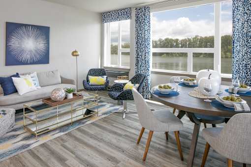 A modern living room with a grey sofa, a coffee table, and a dining table.
