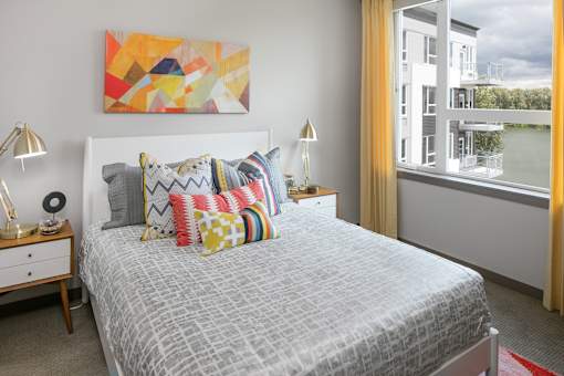 A bedroom with a bed, nightstand, and a painting on the wall