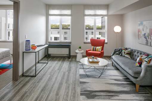 A living room with a grey couch, a red chair, and a white coffee table.