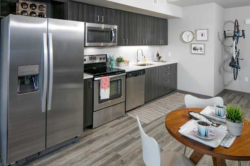 A modern kitchen with a stainless steel refrigerator and a dining table