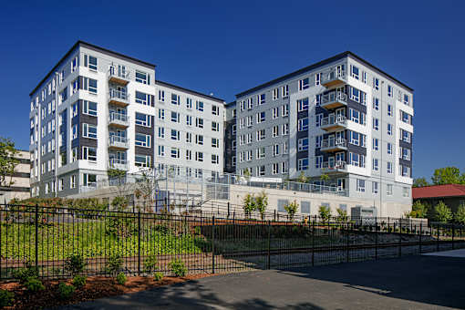 A modern multi-story building with a black fence in front.