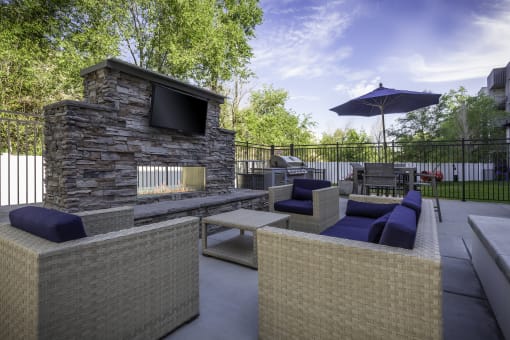 a patio with couches and a television and a stone fireplace