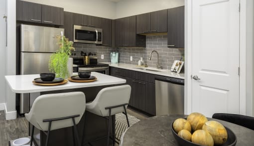 a kitchen with stainless steel appliances and an island with chairs