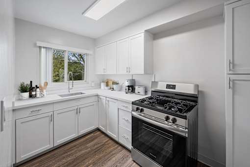 One-Bedroom Affordable Apartments in San Mateo, CA - Hillsdale Garden - Kitchen with Modern Appliances, White Cabinetry, and Hardwood-Style Flooring