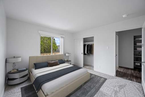 A bedroom with a large bed and a window overlooking trees at Hillsdale Garden Apartments, San Mateo