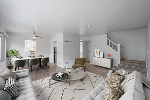 A modern living room with a grey sofa, a coffee table, and a dining table set up at Hillsdale Garden Apartments, San Mateo, 94403