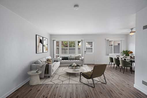 A living room with a grey sofa, a coffee table, and a dining table with chairs at Hillsdale Garden Apartments, 94403