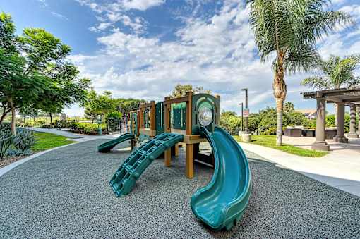 A playground with a green slide and a wooden structure.