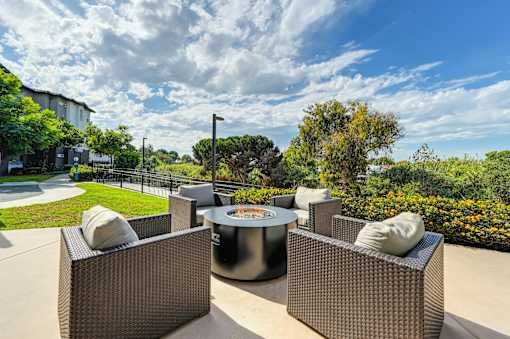 A fire pit and chairs overlooking a green lawn.
