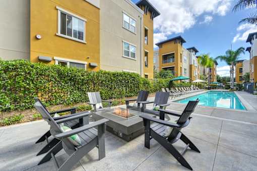 A patio with a table and chairs overlooking a pool.