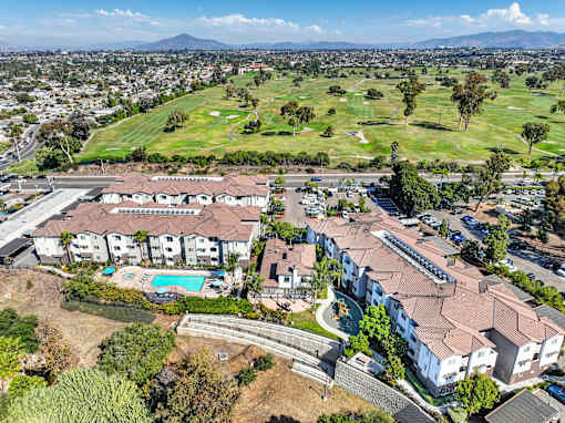 A large apartment complex with a pool and a golf course in the background.